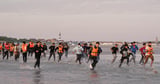 Migrants run across beach to board dinghy in the Channel