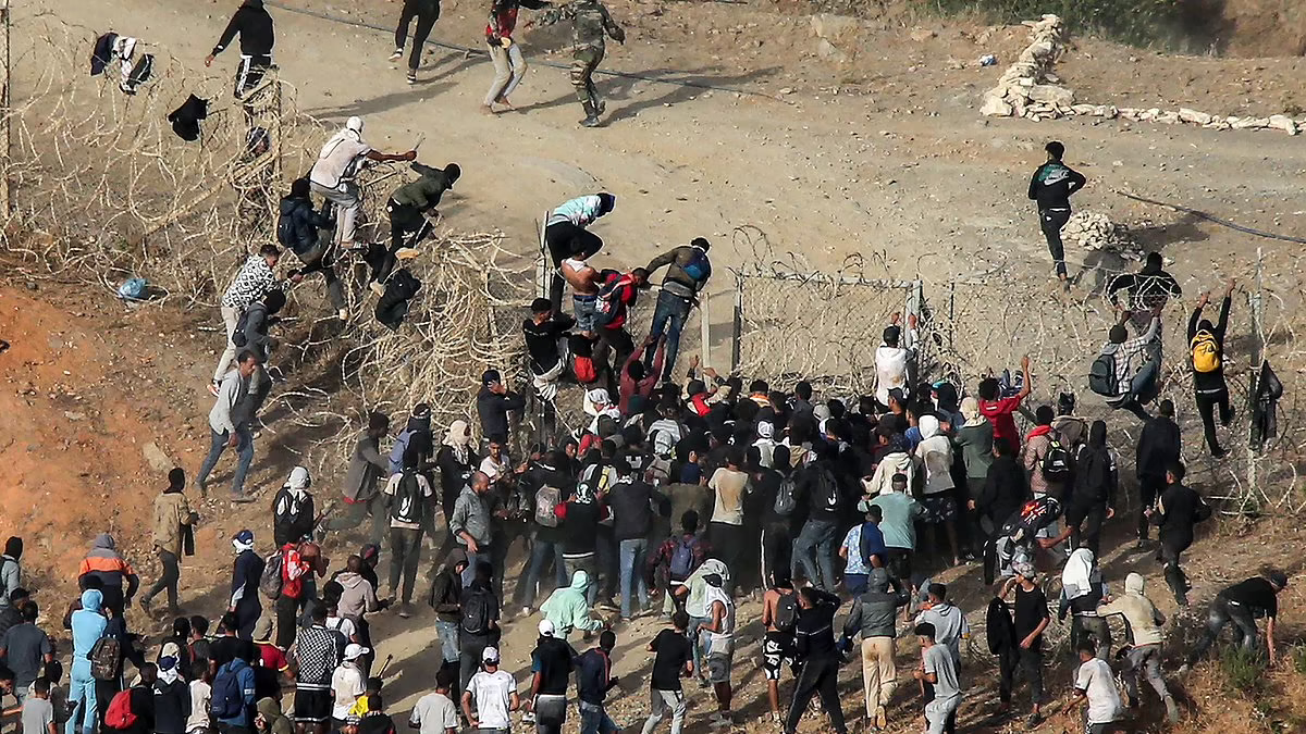 Migrants scale barbed wire fences to storm into enclave in Morocco